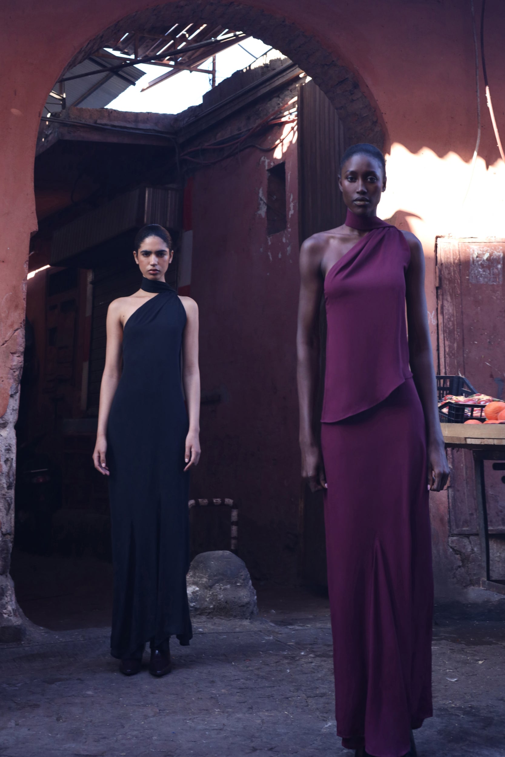 Detail of the Ari Top in burgundy, Textured fabric and asymmetrical neckline in architectural setting.