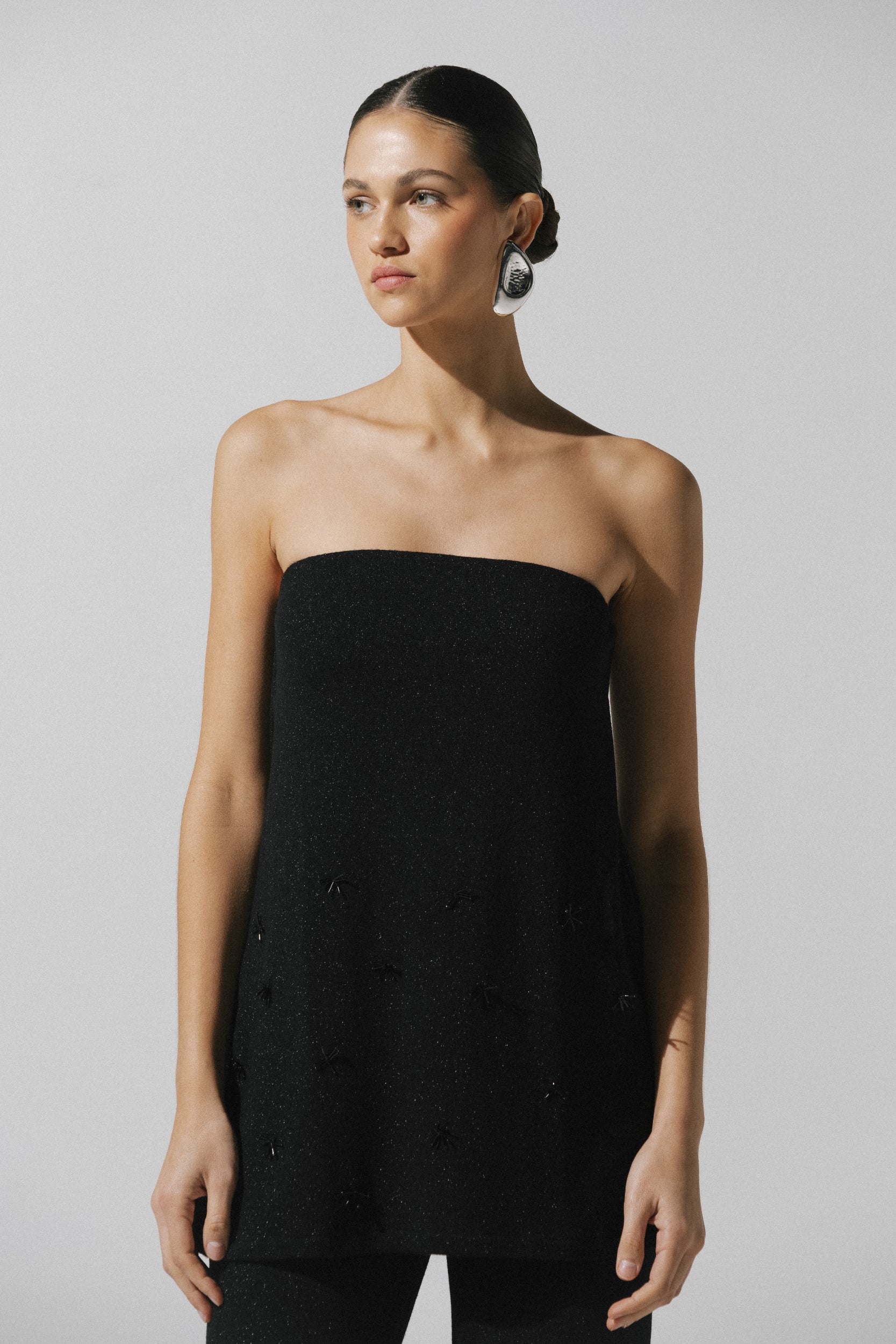 Strapless Suzu Top by Baobab in black Glossy fabric with Embellished detail, paired with pants.