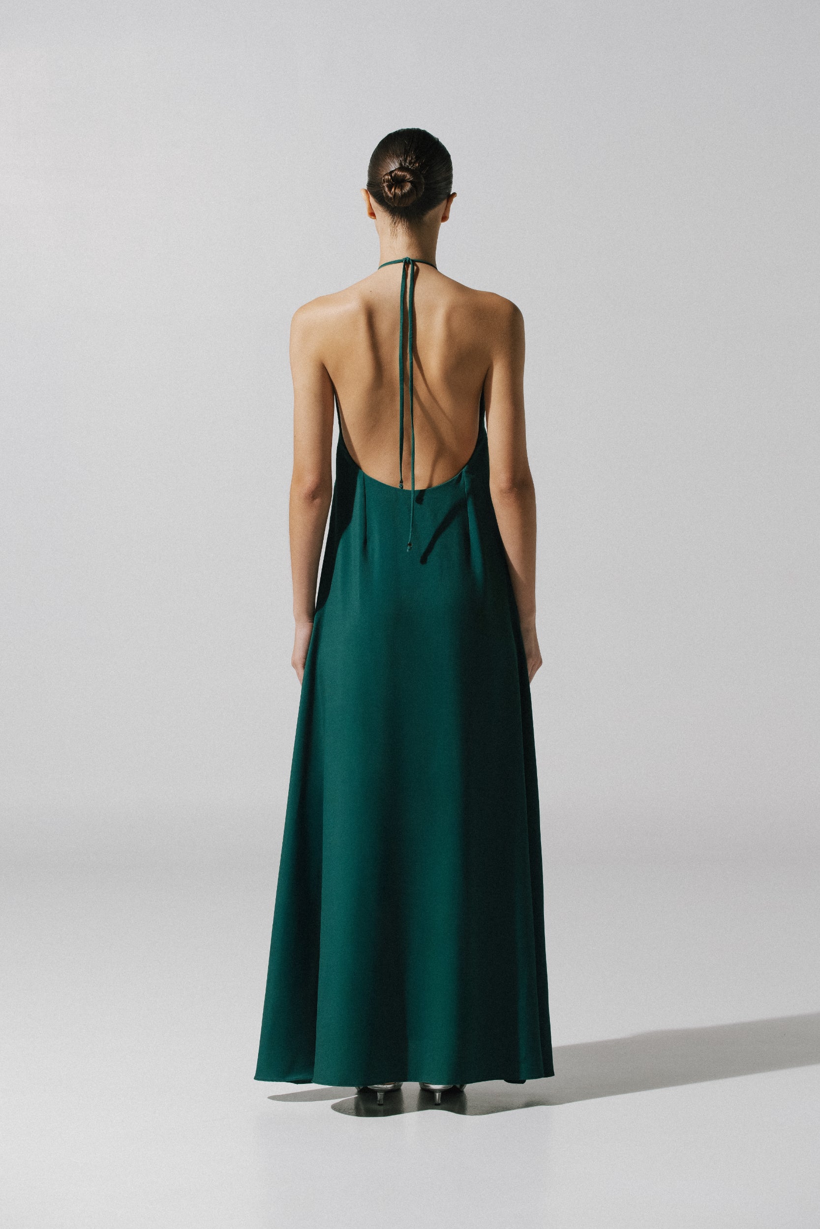 Emerald green Rondine Dress in urban outdoor setting, Halter Neckline and sophisticated fall.
