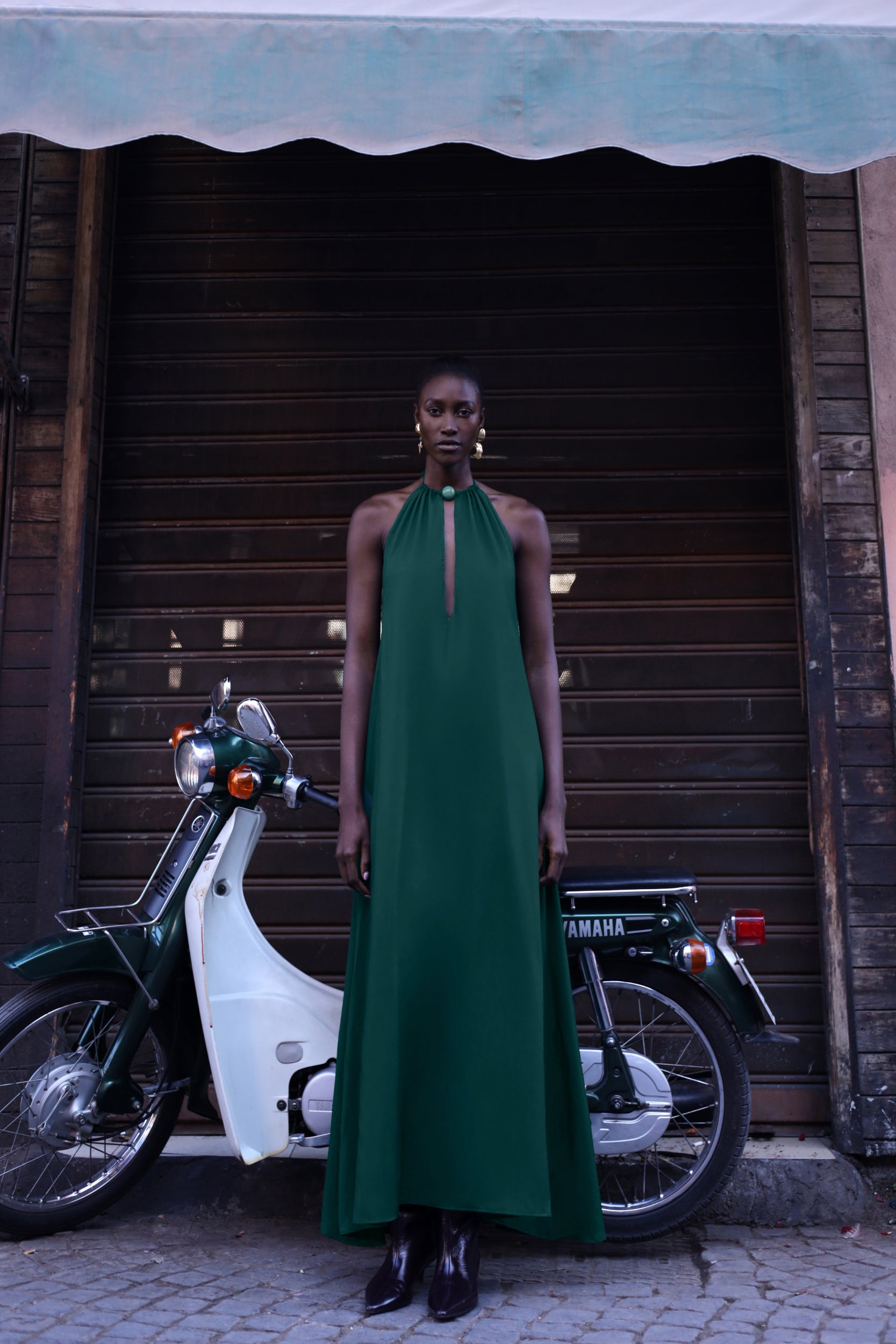 Detail of the Rondine Dress by Baobab, Glossy fabric and Front cutouts in emerald green color.